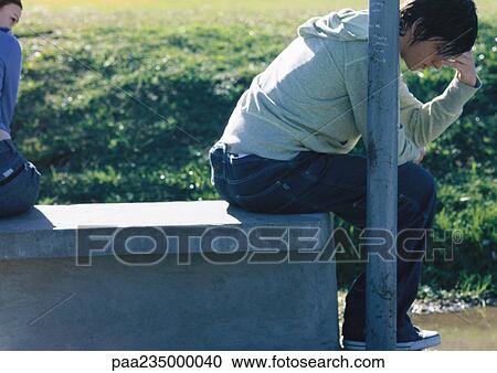 Man sitting next to pole holding his head, woman looking toward him, partial view View Large Photo Image Stock Image - Man sitting next to pole holding his head, woman looking toward him, partial view. Fotosearch