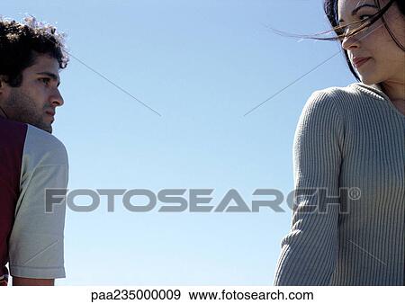 Young man and young woman looking at each other with sky in background. View Large Photo Image Stock Photo - Young man and young woman looking at each other with sky in background.. Fotosearch