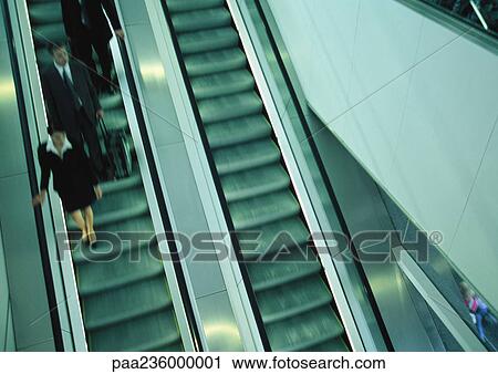 Business people on escalator going down, blurred, high angle view. View Large Photo Image Stock Image - Business people on escalator going down, blurred, high angle view.. Fotosearch