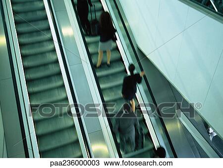Stock Image - Business people on escalator going up, blurred, high angle view. Fotosearch