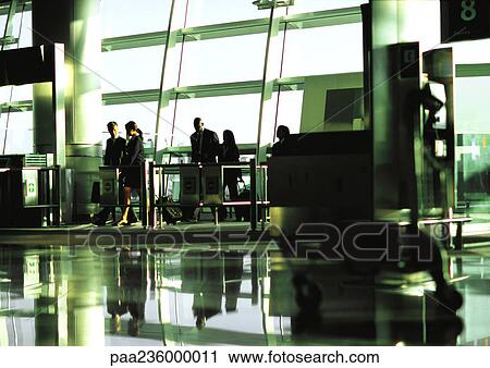 Stock Image - Business people walking through airport terminal gate in the distance.. Fotosearch