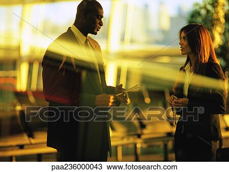 Businessman and businesswoman talking in airport terminal. View Large Photo Image Stock Image - Businessman and businesswoman talking in airport terminal.. Fotosearch
