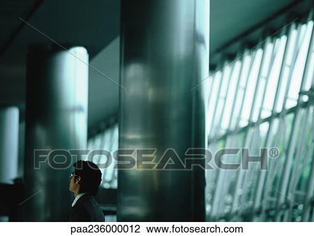 Businessman standing between two large metal columns. View Large Photo Image Stock Image - Businessman standing between two large metal columns.. Fotosearch