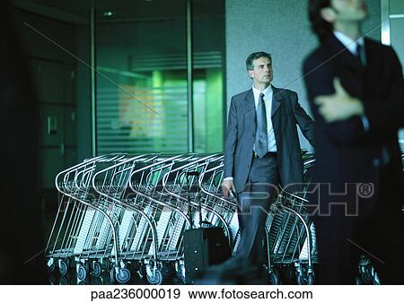 Businessmen standing in front of airport luggage carts. View Large Photo Image Stock Photo - Businessmen standing in front of airport luggage carts.. Fotosearch