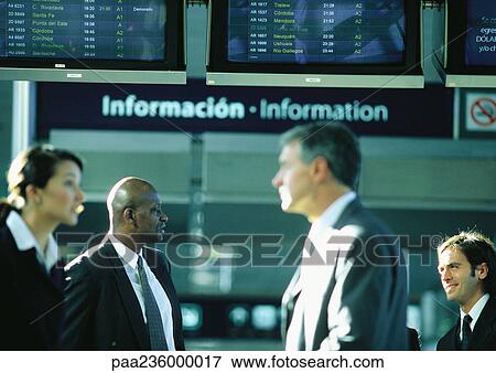 Stock Photo - Businesspeople talking in front of an airport information sign.. Fotosearch