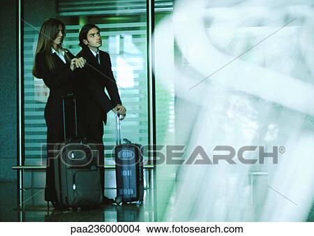 Man and woman standing with suitcases, woman looking at watch. View Large Photo Image Picture - Man and woman standing with suitcases, woman looking at watch.. Fotosearch
