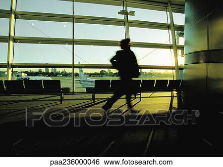 Silhouette of businessperson hurrying through airport terminal. View Large Photo Image Stock Photograph - Silhouette of businessperson hurrying through airport terminal.. Fotosearch