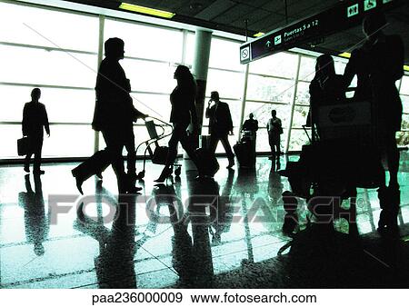 Stock Photo - Silhouettes of business people walking in airport terminal, backlit. Fotosearch
