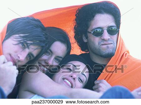 Friends wrapped in orange blanket, close-up. View Large Photo Image Stock Photo - Friends wrapped in orange blanket, close-up.. Fotosearch