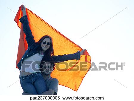 Stock Photography - Man carrying woman stretching orange cloth. Fotosearch