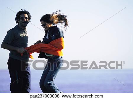Man laughing, restraining woman with orange cloth View Large Photo Image Stock Photo - Man laughing, restraining woman with orange cloth. Fotosearch