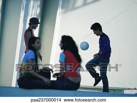 Two women talking in foreground, blurred, two men playing soccer. View Large Photo Image Picture - Two women talking in foreground, blurred, two men playing soccer.. Fotosearch