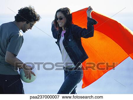 Woman carrying orange cloth looking at man with ball. View Large Photo Image Stock Photo - Woman carrying orange cloth looking at man with ball.. Fotosearch