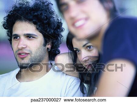 Woman leaning on man, second man smiling, blurred in foreground View Large Photo Image Stock Photo - Woman leaning on man, second man smiling, blurred in foreground. Fotosearch