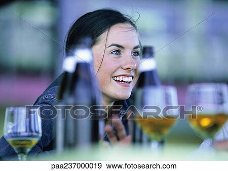 Woman smiling at table with bottles and glasses.. View Large Photo Image Stock Photo - Woman smiling at table with bottles and glasses... Fotosearch