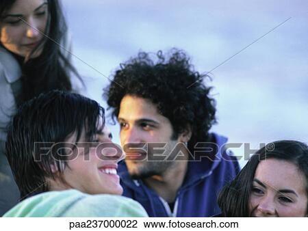 Stock Image - Young people sitting together, close-up.. Fotosearch