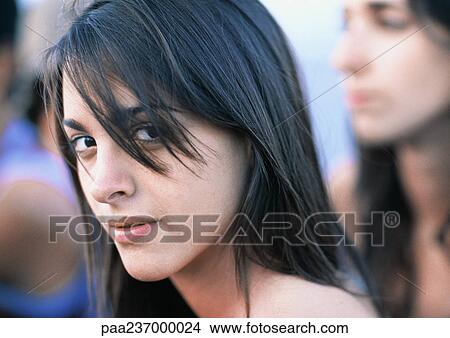 Young woman looking at camera, close-up portrait, friends in background View Large Photo Image Picture - Young woman looking at camera, close-up portrait, friends in background. Fotosearch