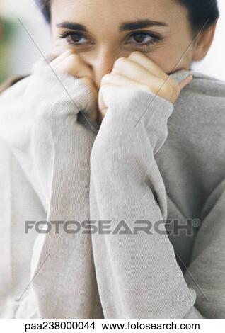 Woman holding on to ends of sleeves, covering lower part of face, head and shoulders, parital view, close-up View Large Photo Image Picture - Woman holding on to ends of sleeves, covering lower part of face, head and shoulders, parital view, close-up. Fotosearch