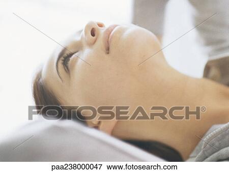 Stock Photo - Woman lying with hands behind head, close-up. Fotosearch