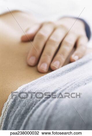 Stock Image - Woman's hand on bare stomach, close-up. Fotosearch