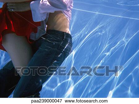 Stock Photo - Couple embracing, mid-section, underwater view. Fotosearch