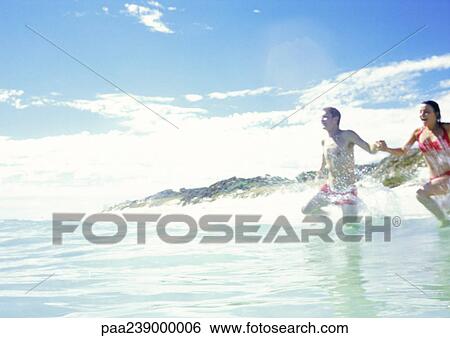 Stock Photograph - Couple running into ocean. Fotosearch
