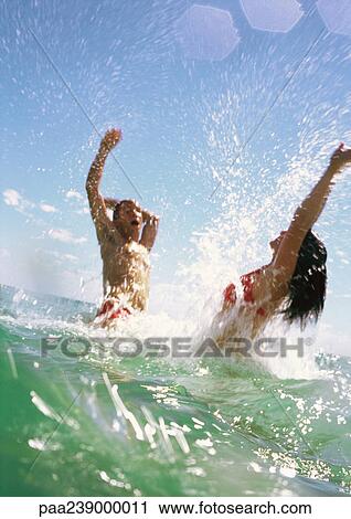 Stock Image - Couple splashing in sea. Fotosearch