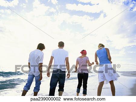 Stock Image - Group of people on beach, rear view. Fotosearch
