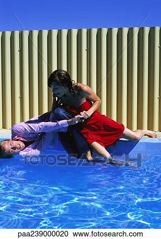Man and woman on side of swimming pool, falling into water View Large Photo Image Stock Image - Man and woman on side of swimming pool, falling into water. Fotosearch