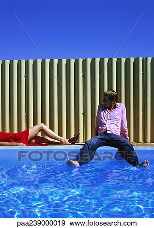 Stock Photo - Man and woman on side of swimming pool. Fotosearch