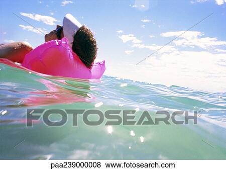 Stock Photo - Man on air mattress, floating. Fotosearch
