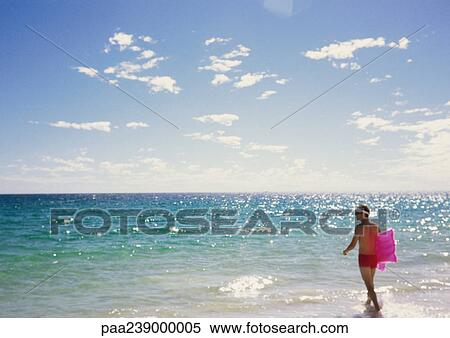 Man walking into ocean with air mattress View Large Photo Image Stock Photography - Man walking into ocean with air mattress. Fotosearch