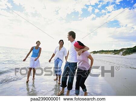Stock Image - Two couples walking on beach. Fotosearch