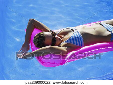 Stock Image - Woman lying on air mattress, elevated view . Fotosearch