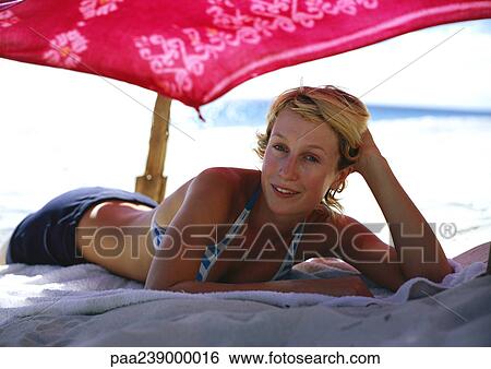 Woman lying on beach under parasol View Large Photo Image Stock Photograph - Woman lying on beach under parasol. Fotosearch