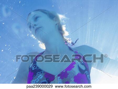 Stock Photo - Woman underwater, low angle view. Fotosearch