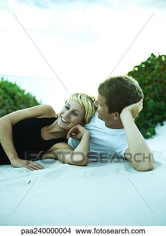 Picture - Couple lying on sand side by side. Fotosearch