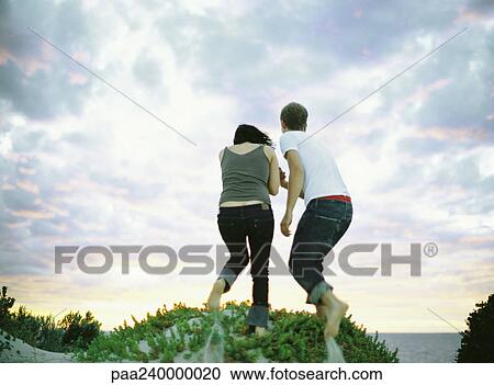 Couple on sand dune, rear view View Large Photo Image Stock Image - Couple on sand dune, rear view. Fotosearch