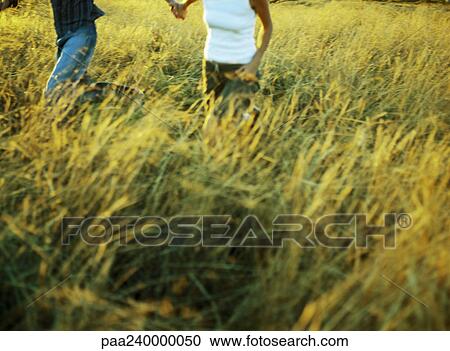 Couple running in field of tall grass, mid-section View Large Photo Image Stock Image - Couple running in field of tall grass, mid-section. Fotosearch