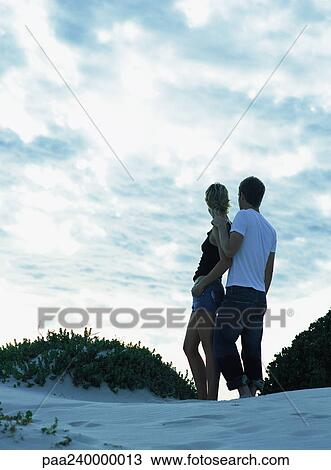 Couple standing together on sand dune, rear view View Large Photo Image Stock Image - Couple standing together on sand dune, rear view. Fotosearch