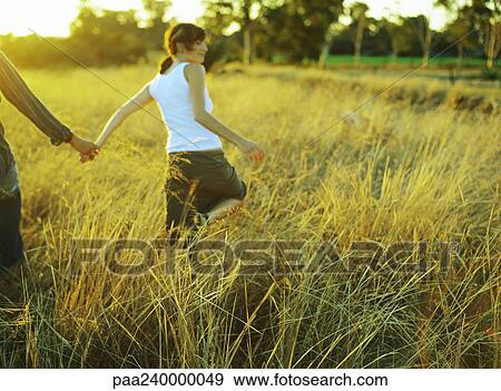 Couple walking in field of tall grass View Large Photo Image Stock Photo - Couple walking in field of tall grass. Fotosearch