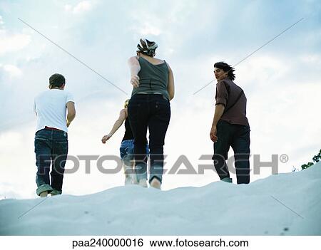 Four people walking on sand, rear view View Large Photo Image Stock Photograph - Four people walking on sand, rear view. Fotosearch