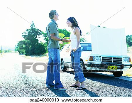 Man and woman standing in front of car with open hood View Large Photo Image Stock Image - Man and woman standing in front of car with open hood. Fotosearch