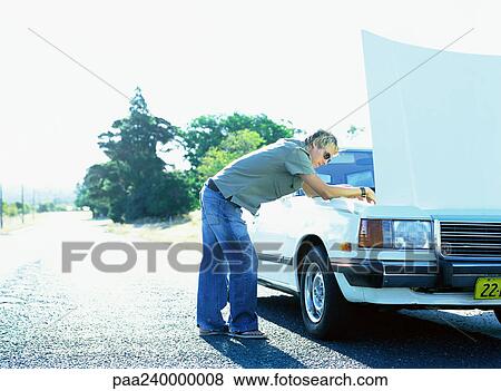 Stock Photo - Man looking under car hood. Fotosearch
