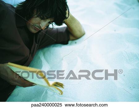 Man lying on sand, reading, close-up View Large Photo Image Stock Photography - Man lying on sand, reading, close-up. Fotosearch