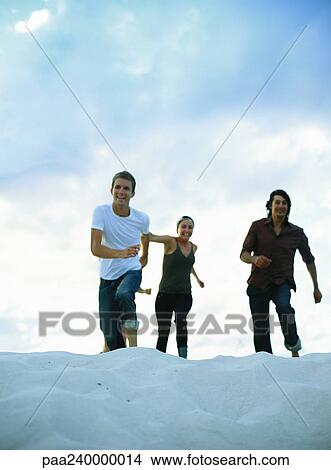 Two men and woman running on sand View Large Photo Image Picture - Two men and woman running on sand. Fotosearch