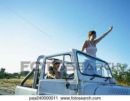 Two women in 4x4 vehicle, one standing up, waving View Large Photo Image Stock Image - Two women in 4x4 vehicle, one standing up, waving. Fotosearch