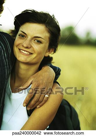 Woman with man's arm around her smiling at camera, portrait View Large Photo Image Stock Image - Woman with man's arm around her smiling at camera, portrait. Fotosearch