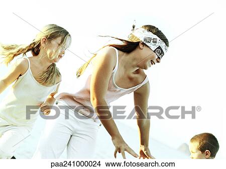 Blindfolded girl reaching and smiling outdoors, two children in background View Large Photo Image Picture - Blindfolded girl reaching and smiling outdoors, two children in background. Fotosearch