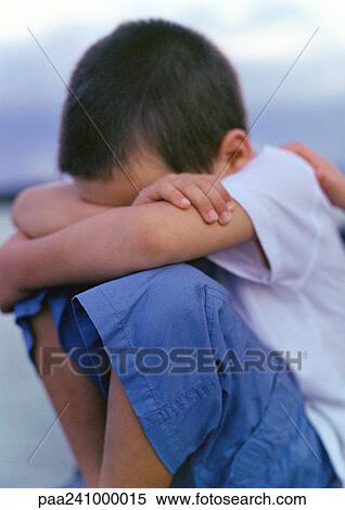 Boy sitting with knees up and arms folded, hiding head View Large Photo Image Stock Photography - Boy sitting with knees up and arms folded, hiding head. Fotosearch
